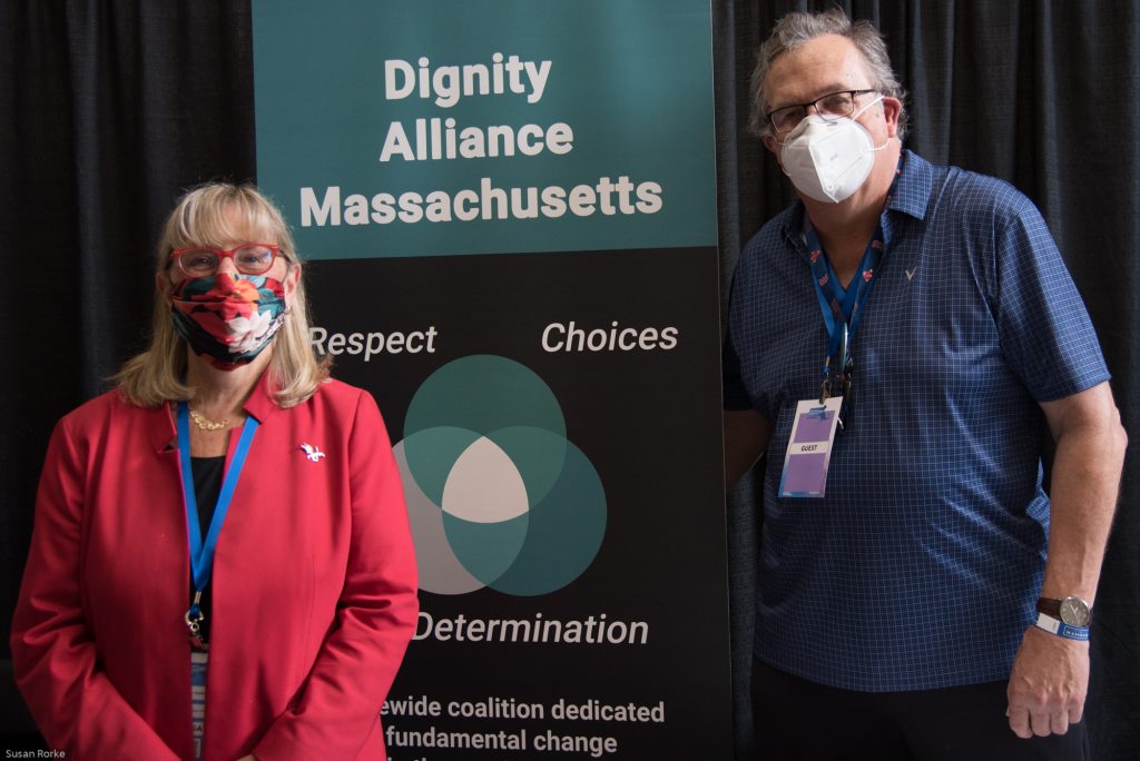 Senate President Karen Spilka with Paul Lanzikos in front of DignityMA banner.