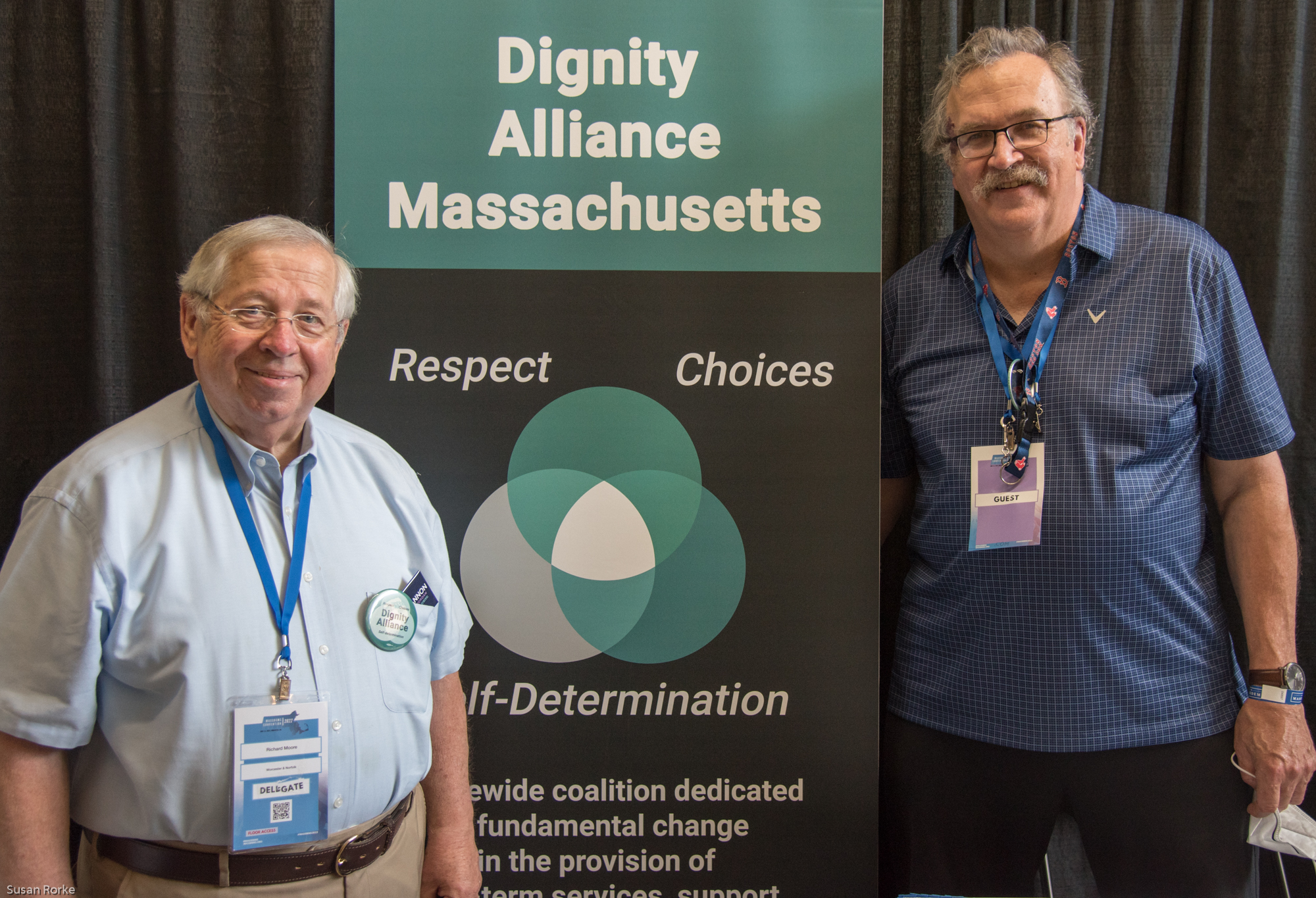 Richard Moore and Paul Lanzikos in front of the Dignity Alliance MA banner