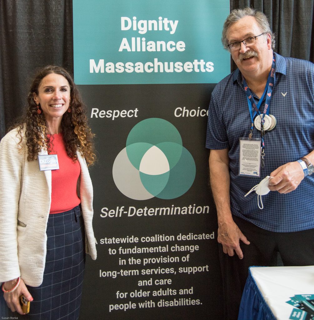 State Auditor Diane DiZoglio with Paul Lanzikos in front of DignityMA banner.