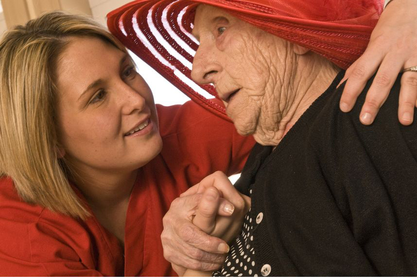 Woman in red comforting older woman in a red hat